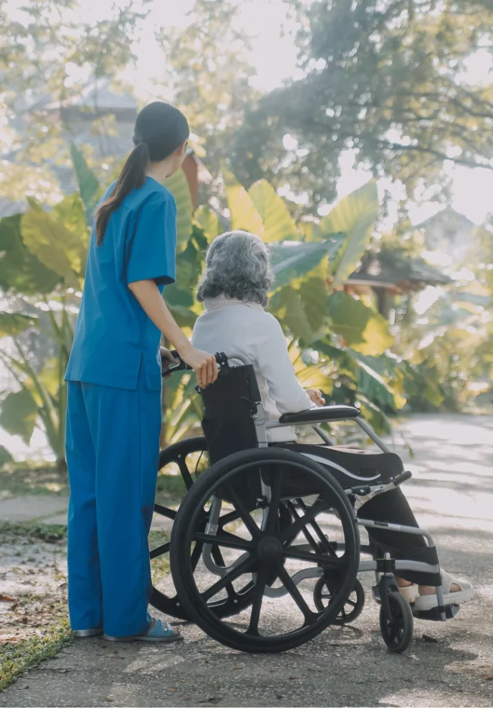 Nurse and patient in a wheel chair looking into the distance on the side of a road.